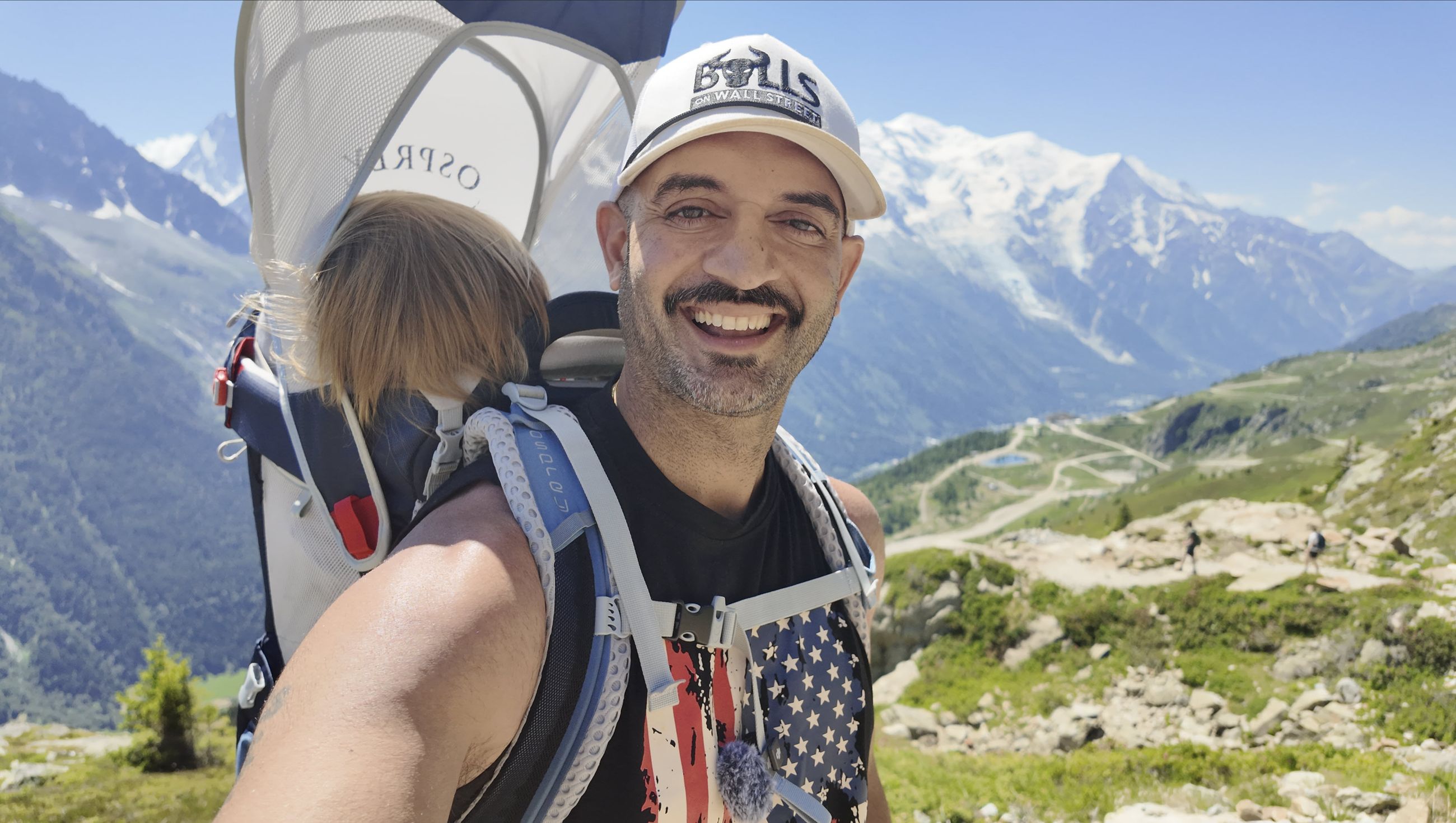 Kunal Desai hiking in the Alps with his son, wearing a Bulls on Wall Street cap